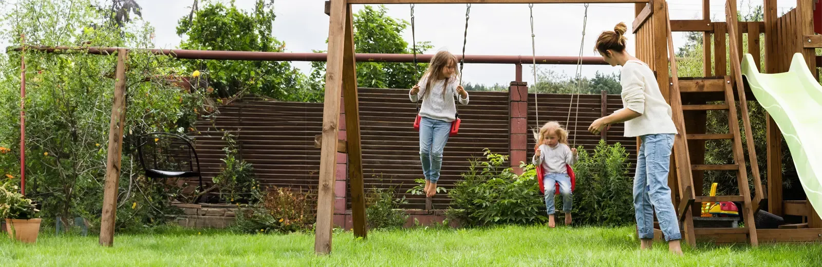 family playing on swing set in backyard 